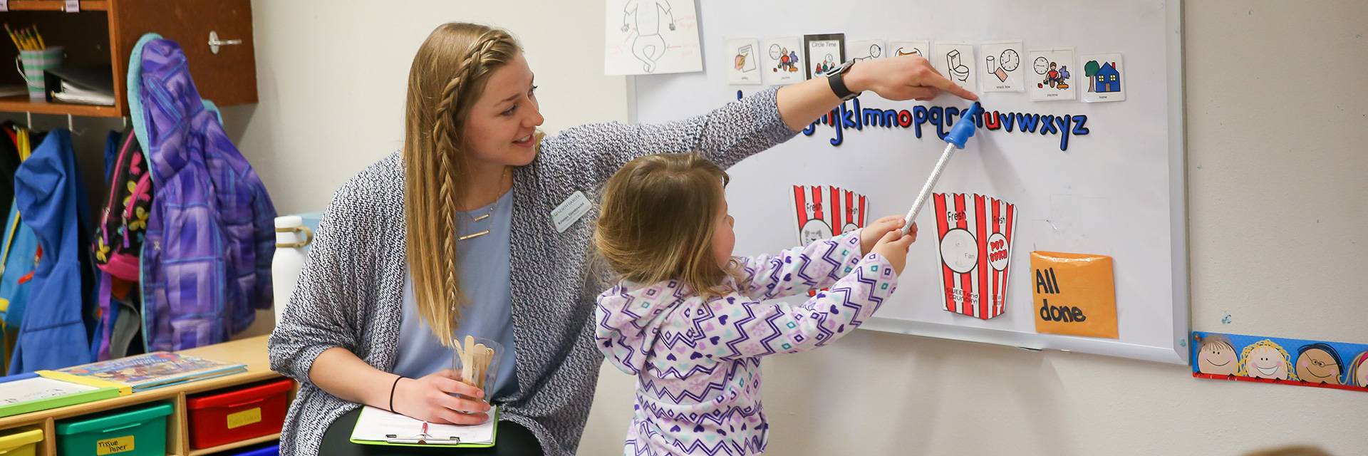 working with a child on letters in classroom